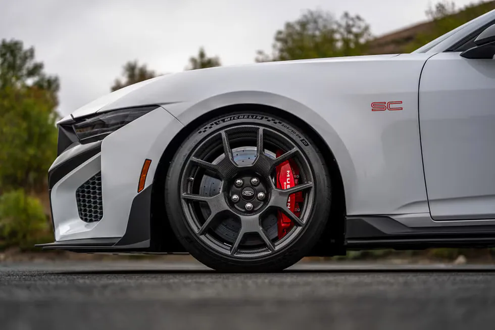 Close-up of a sports car's front wheel showcasing a sleek design and red brake calipers.