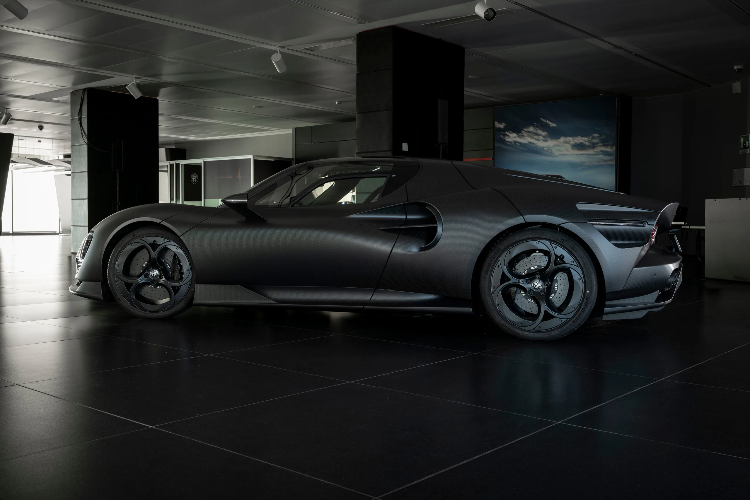 Sleek black supercar displayed in a modern showroom with polished floors and ambient lighting.