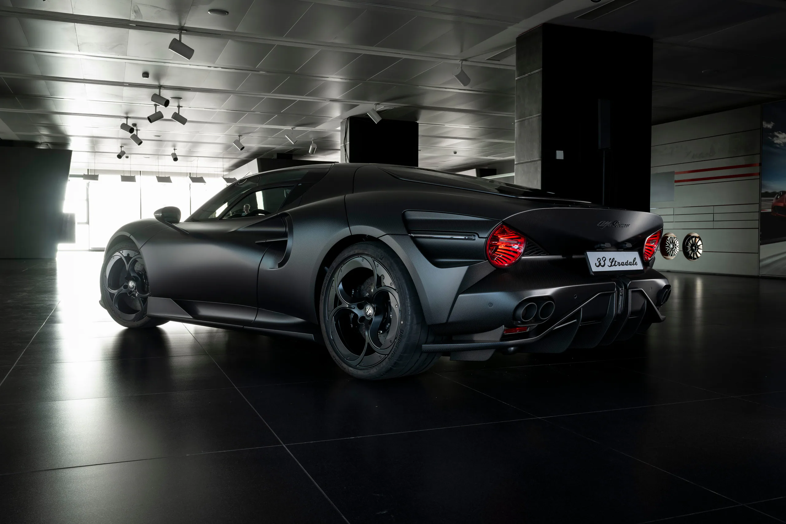 Sleek black sports car parked in a modern showroom with dramatic lighting and polished floors.