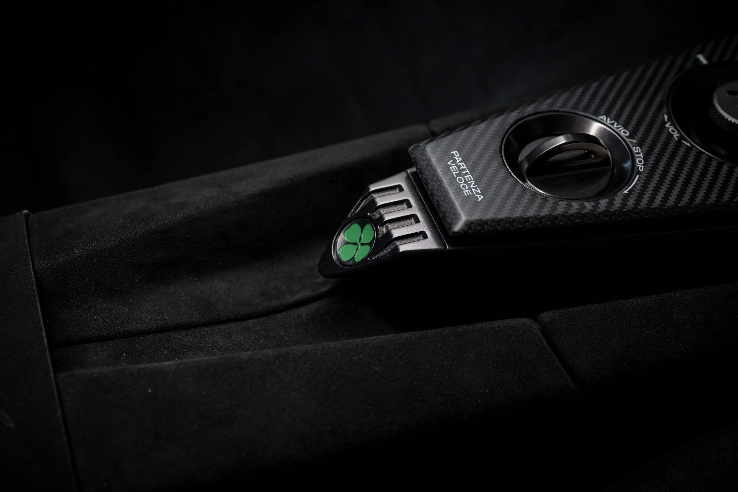 Close-up of a car's control panel featuring a black and green switch amidst a dark interior.