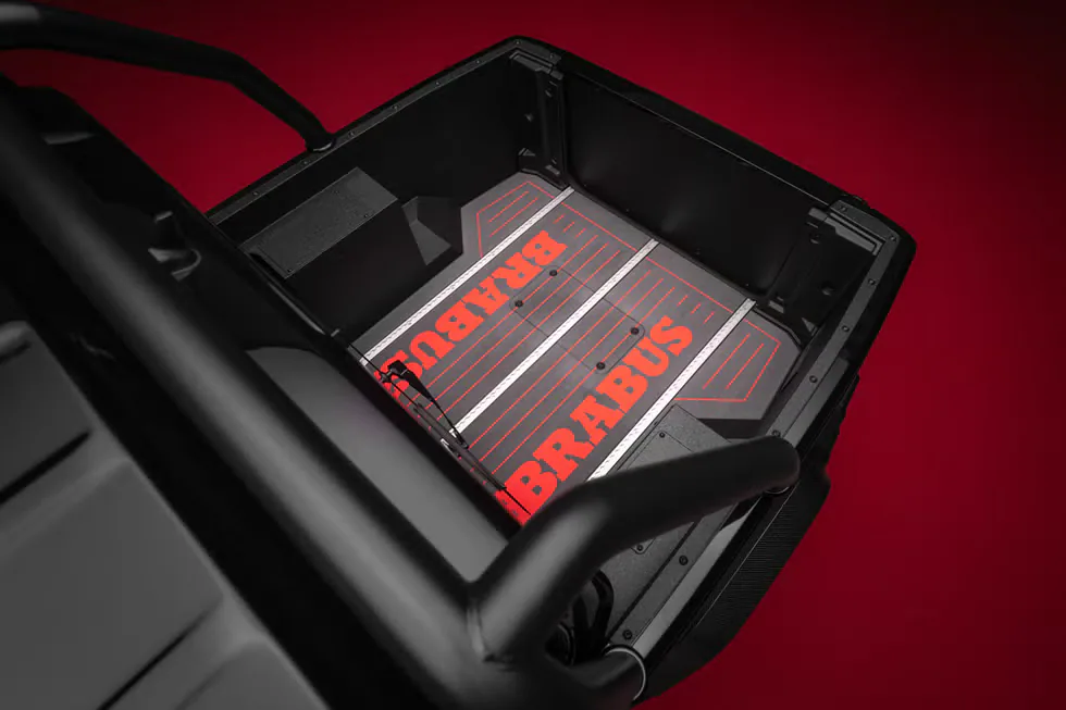 Black cargo area featuring red BRABUS branding on the floor and a textured surface, set against a red background.
